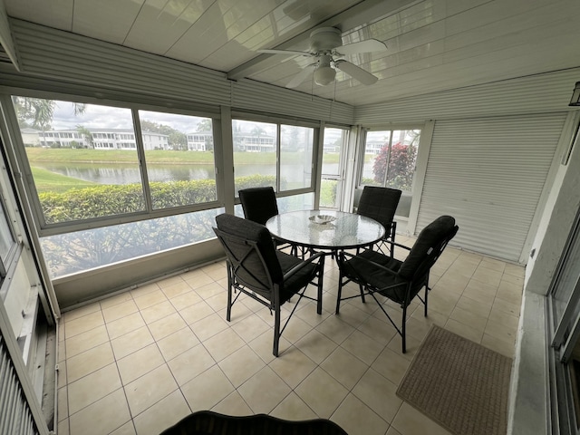 sunroom with a ceiling fan and a water view