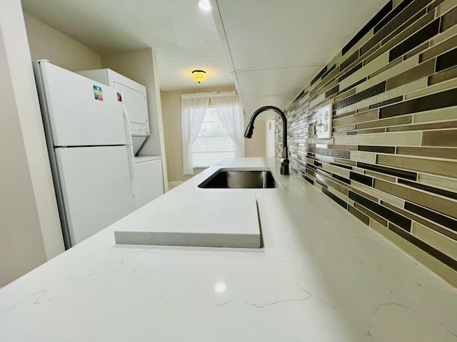 kitchen with freestanding refrigerator, white cabinets, a sink, and wooden walls