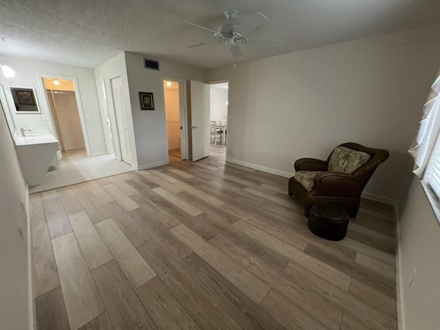 unfurnished room with baseboards, light wood-style flooring, visible vents, and a textured ceiling