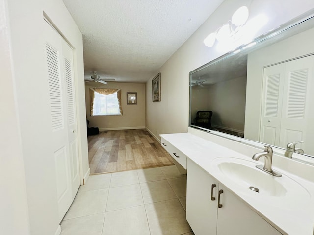 bathroom featuring a textured ceiling, tile patterned flooring, vanity, a ceiling fan, and a closet