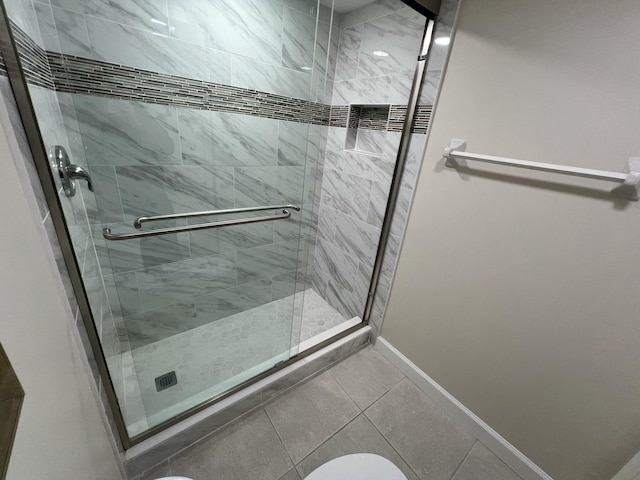 bathroom featuring a shower stall, baseboards, and tile patterned floors