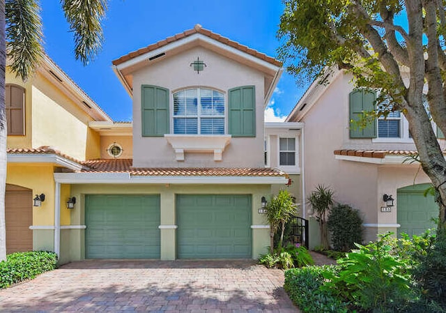 view of front of home featuring an attached garage, a tiled roof, decorative driveway, and stucco siding