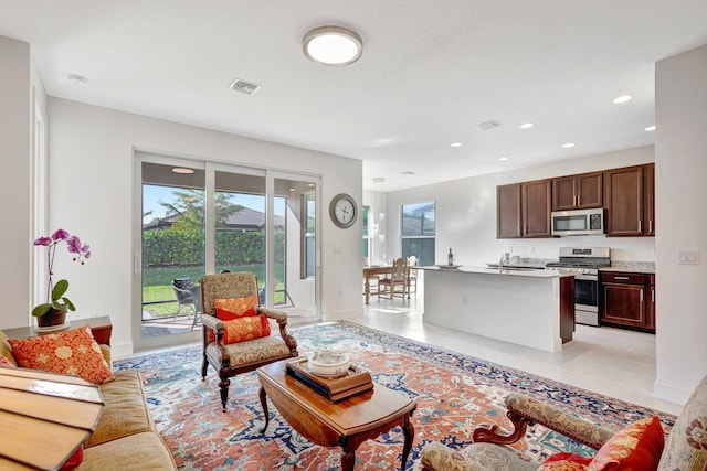 living room featuring baseboards, light tile patterned flooring, visible vents, and recessed lighting