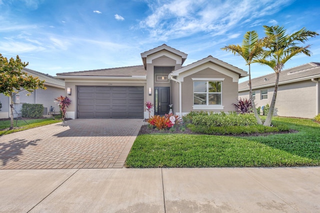 single story home with a front lawn, decorative driveway, an attached garage, and stucco siding