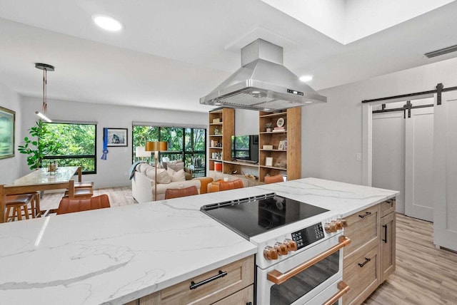 kitchen featuring a barn door, high end stove, open floor plan, light brown cabinetry, and island exhaust hood