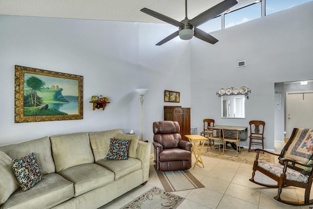 living room featuring light tile patterned floors, ceiling fan, a high ceiling, and visible vents