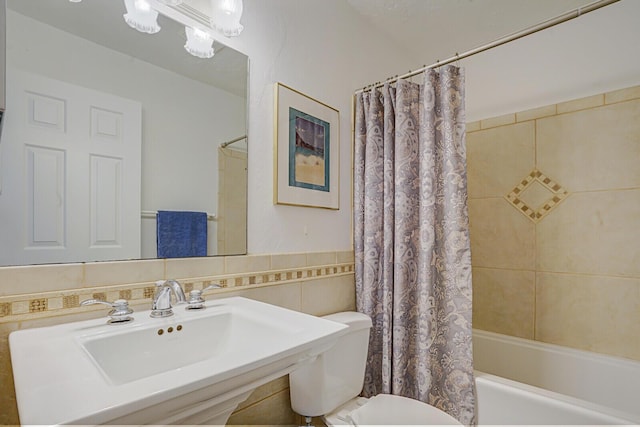 bathroom with shower / bath combo, a sink, tile walls, and toilet