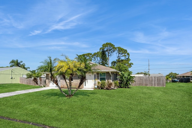 view of front of home with concrete driveway, brick siding, a front lawn, and fence