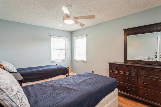 bedroom featuring light wood-style flooring, ceiling fan, and a textured ceiling