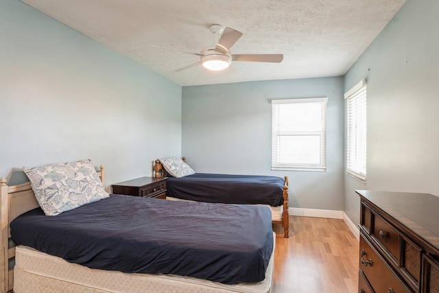 bedroom with light wood-type flooring, a ceiling fan, baseboards, and a textured ceiling