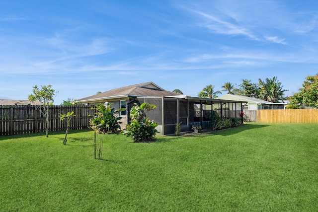 rear view of property with a sunroom, brick siding, a yard, and a fenced backyard