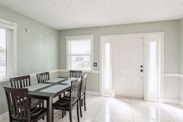 dining space with a textured ceiling, baseboards, and light tile patterned floors