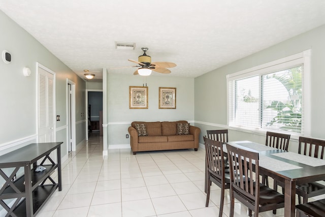 dining space with a ceiling fan, visible vents, a textured ceiling, and light tile patterned floors