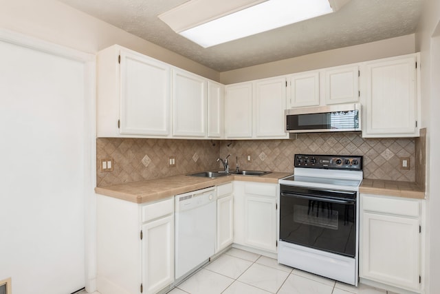 kitchen with white dishwasher, stainless steel microwave, white cabinets, and range with electric stovetop