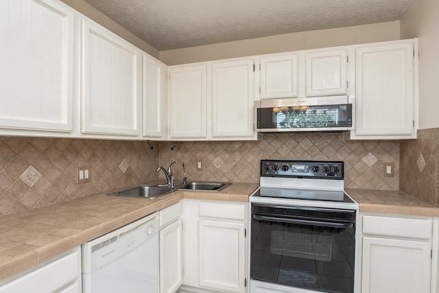 kitchen with stainless steel microwave, white dishwasher, white cabinetry, a sink, and range with electric stovetop