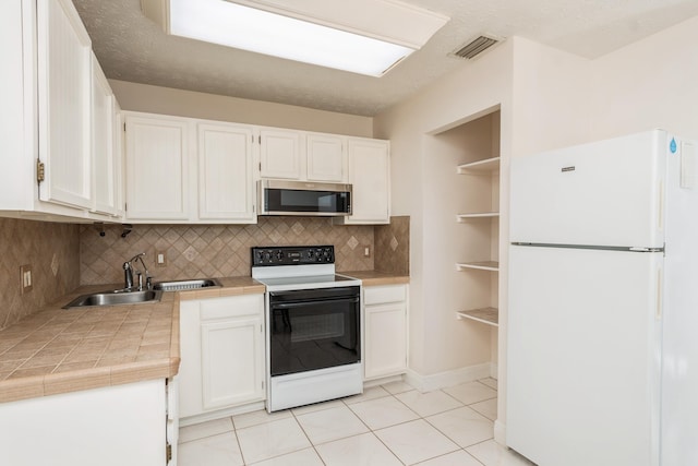 kitchen featuring open shelves, stainless steel microwave, freestanding refrigerator, white cabinetry, and range with electric cooktop