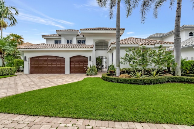 mediterranean / spanish-style house with a garage, decorative driveway, french doors, a front lawn, and stucco siding