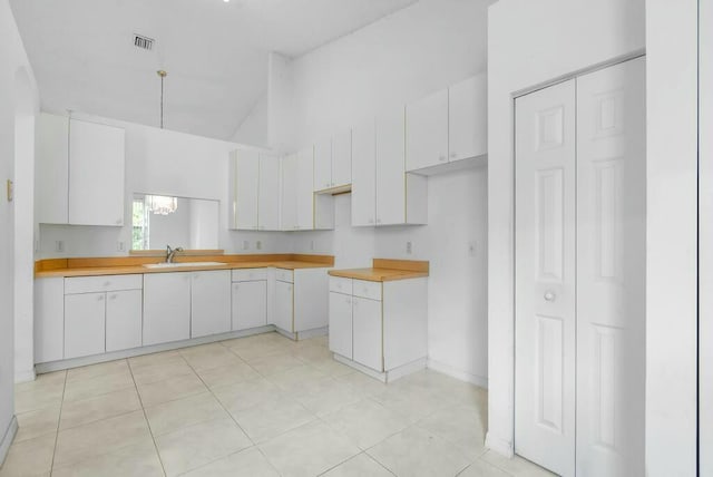 kitchen featuring high vaulted ceiling, visible vents, white cabinetry, and a sink