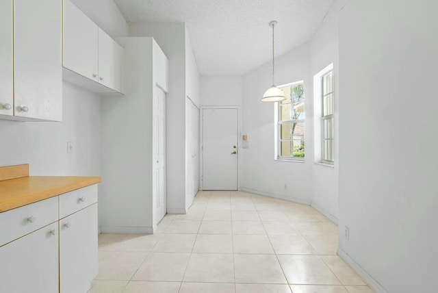 kitchen featuring light tile patterned floors, white cabinetry, light countertops, decorative light fixtures, and baseboards