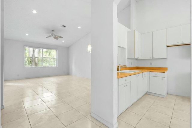 kitchen with light tile patterned floors, white cabinetry, a ceiling fan, visible vents, and a sink