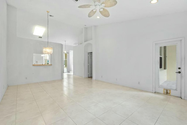 unfurnished living room featuring arched walkways, recessed lighting, light tile patterned floors, and ceiling fan with notable chandelier