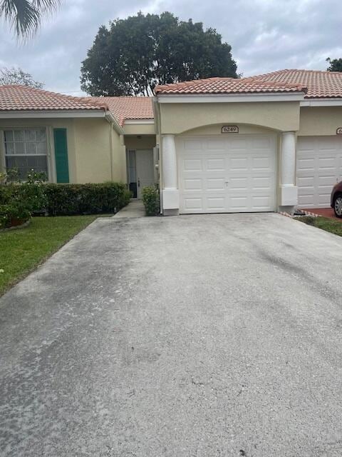 view of front of property featuring a garage, concrete driveway, a tiled roof, and stucco siding