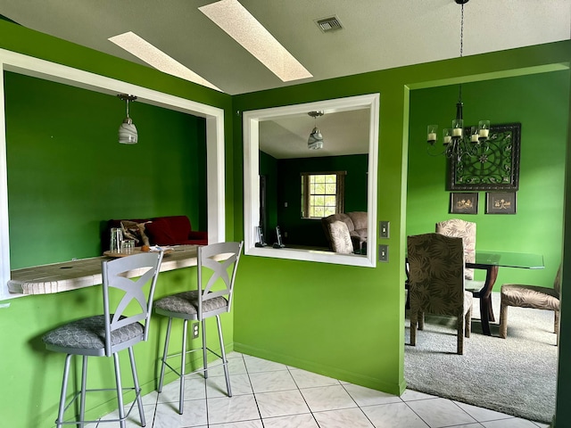 kitchen featuring a chandelier, light tile patterned flooring, a breakfast bar, visible vents, and vaulted ceiling