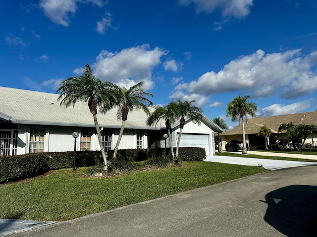 view of front of home featuring driveway, a garage, a front lawn, and stucco siding