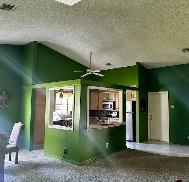 kitchen featuring light carpet, light tile patterned floors, visible vents, lofted ceiling, and stainless steel appliances