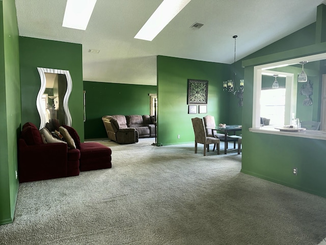 living area featuring lofted ceiling with skylight, a notable chandelier, carpet floors, and baseboards