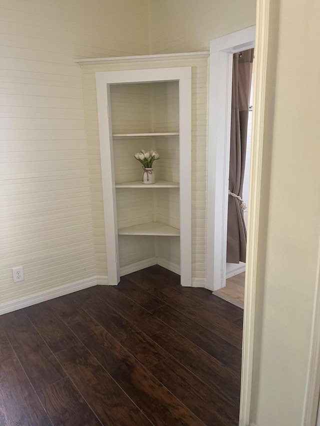 interior space featuring baseboards and dark wood finished floors