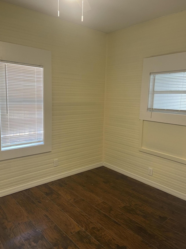 spare room with dark wood-style floors, a wealth of natural light, and baseboards