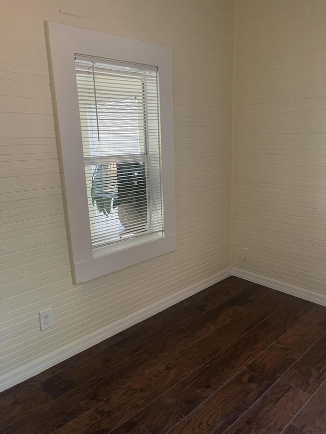 spare room featuring dark wood-style flooring and baseboards