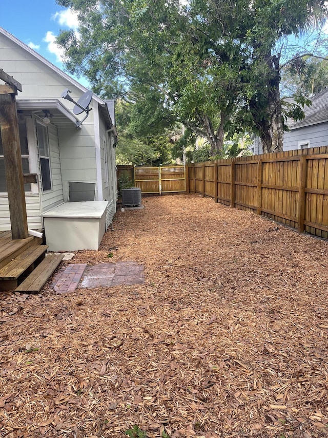 view of yard with entry steps, a fenced backyard, and central air condition unit