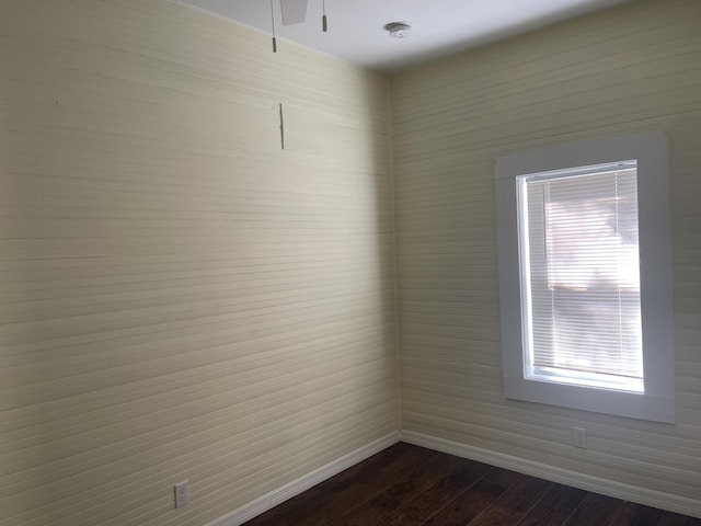 spare room featuring baseboards and dark wood-type flooring