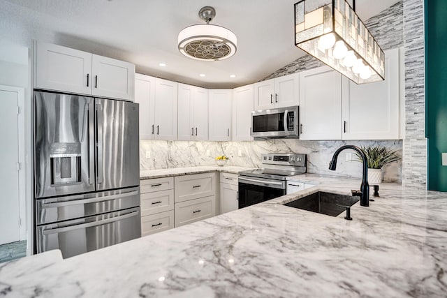 kitchen with stainless steel appliances, tasteful backsplash, a sink, and light stone countertops