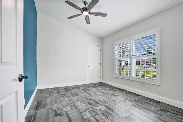 unfurnished room featuring vaulted ceiling, a textured ceiling, baseboards, and ceiling fan