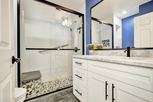 full bathroom featuring a stall shower, visible vents, vanity, and toilet