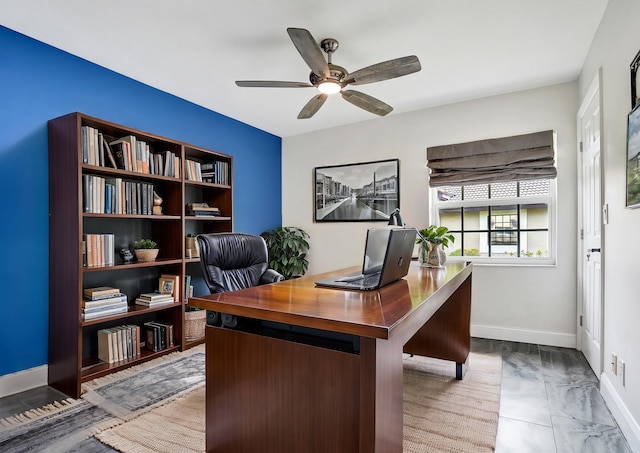 office space featuring a ceiling fan and baseboards