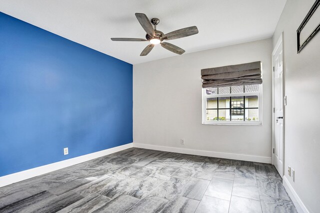 empty room with a ceiling fan and baseboards