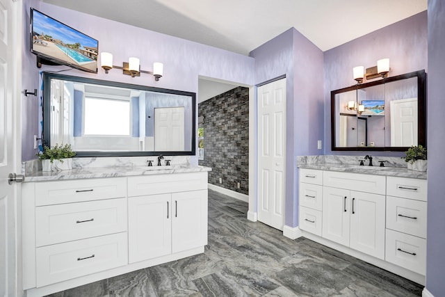 full bathroom featuring marble finish floor, two vanities, and a sink