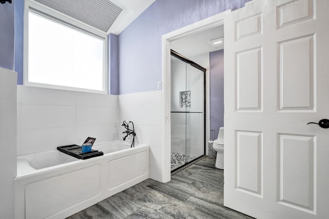 bathroom with toilet, a garden tub, a shower stall, and tile walls