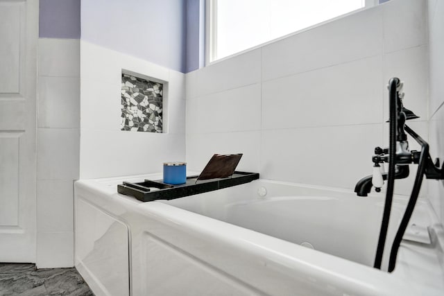 bathroom featuring tile walls and a bath