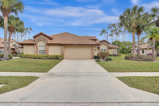 mediterranean / spanish-style home with a garage, concrete driveway, a tiled roof, stucco siding, and a front lawn