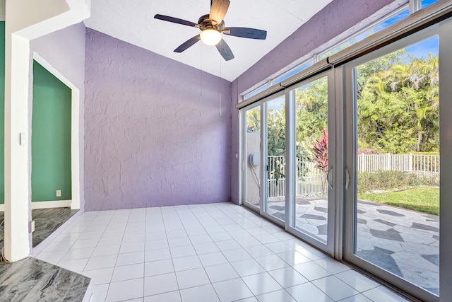 spare room featuring ceiling fan, a textured wall, and tile patterned floors