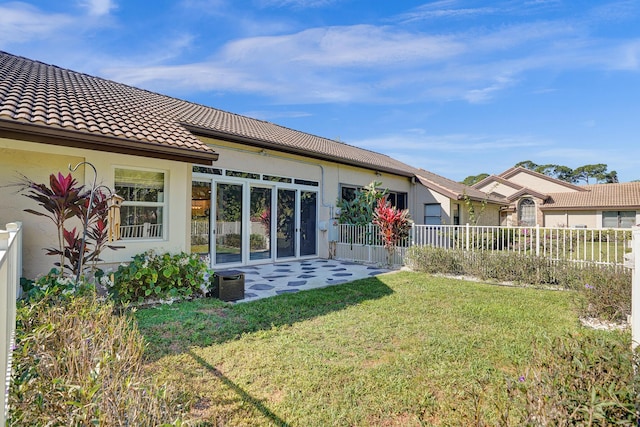 back of house featuring central AC unit, a tile roof, fence, a yard, and stucco siding