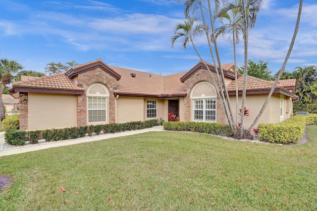 view of front of home featuring a tile roof, a front lawn, and stucco siding