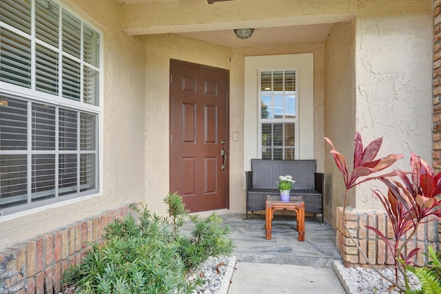 doorway to property with a porch and stucco siding