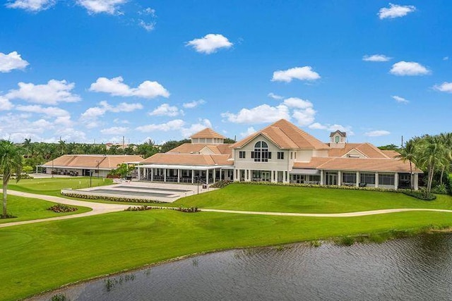 back of house with a lawn and a water view