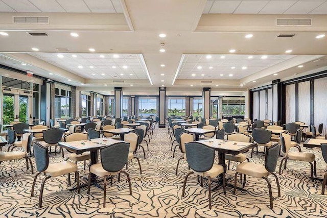 dining room featuring a raised ceiling, visible vents, and plenty of natural light